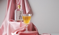 A bottle of Dampfwerk pear brandy sits alongside a glass on pink satin.