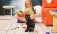 A young girl reads to a cat at the Animal Humane Society.