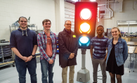 Students gather around a traffic light in an engineering class.
