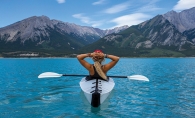 A woman in a kayak looks at some mountains ahead.