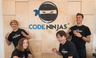 Four kids who learned coding through the Code Ninjas program pose in front of the logo.