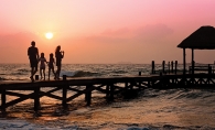 A family enjoys a sunset on the beach on their family vacation.