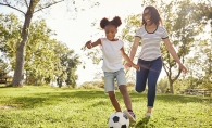 Woman and daughter playing soccer in the park