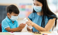 Masked woman and child using hand sanitizer