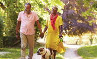 Two senior citizens walk with their pet dog. 