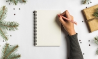 A person writes a to-do list to stay organized during the holidays.