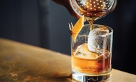 A bartender pours an old fashioned into a glass.