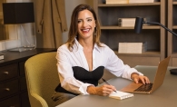 Model wearing a structured white blouse with cropped pants in an office setting.