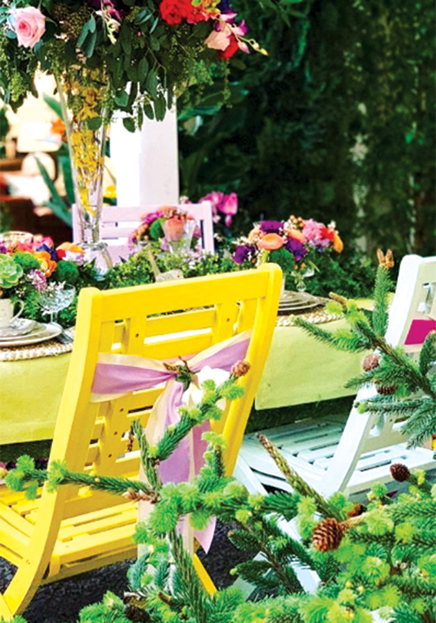 A pair of patio chairs sit by a flower display at the Galleria Garden Party.