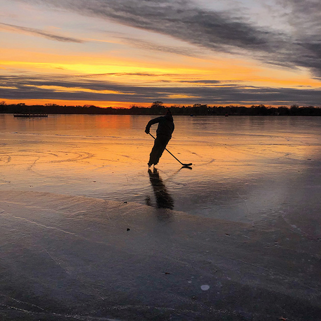 A skater skates on a frozen Minnesota lake at sunset.