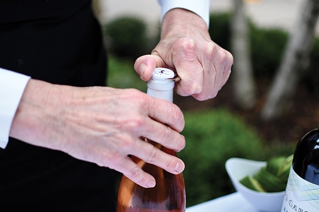 A server opens a bottle of champagne at the Mill City Summer Opera reception.