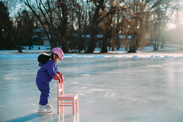 A young girl skates with the aid of a chair on a frozen Minnesota lake.
