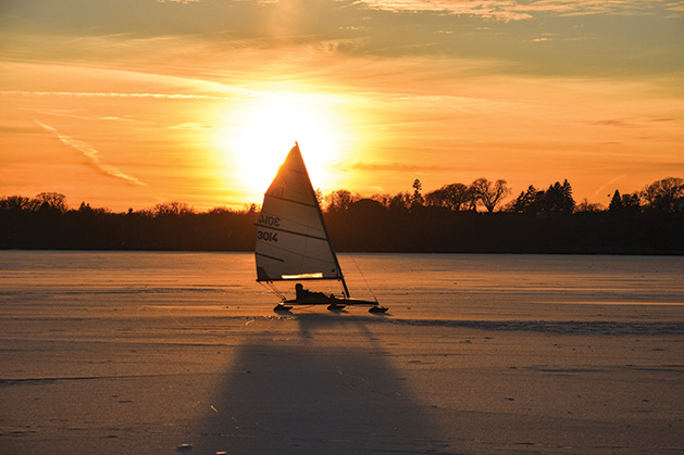 A boat sails on a Minnesota lake as the sun sets in the background.
