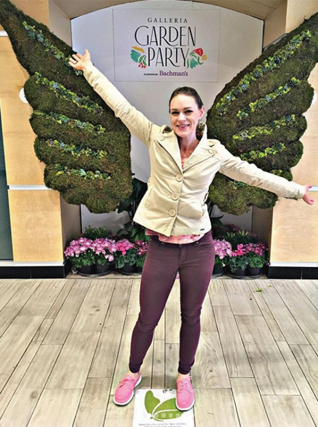 @vanillasparklekitty stands before a pair of floral wings at the Galleria Garden Party