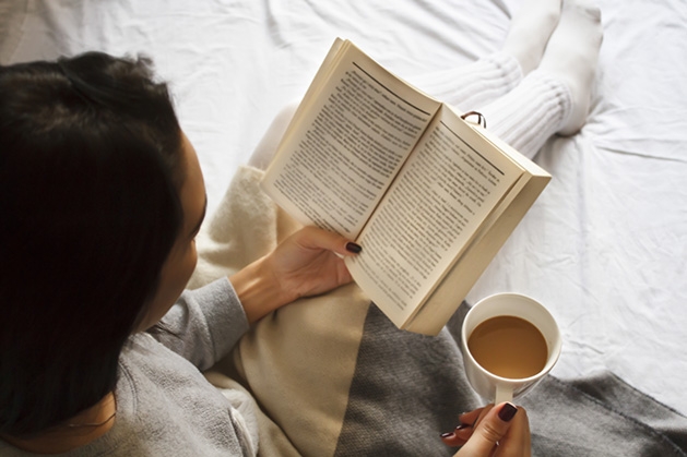 A woman reads Erik Larson's "The Splendid and the Vile" while drinking a cup of coffee.