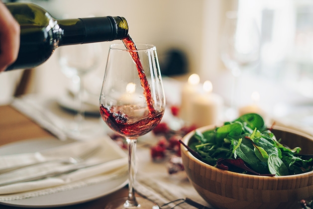 A glass of red wine is poured at a dinner table.