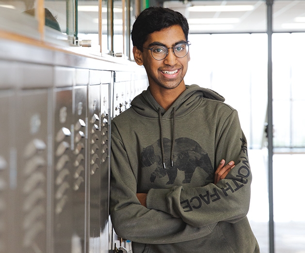 Shrey Ramesh, the Edina High School student honored by the Edina Community Foundation, leans against some lockers.