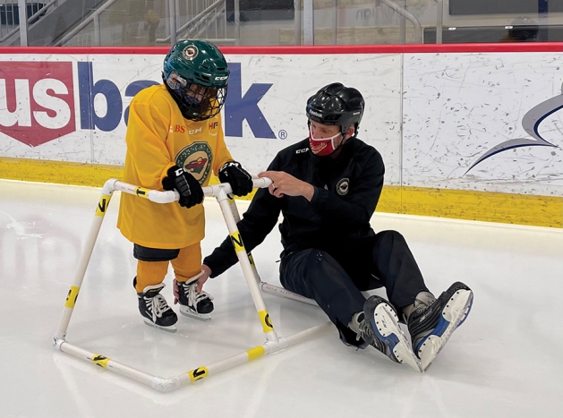 Coach teaches young hockey player to stake