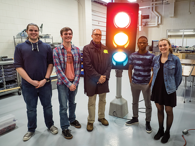 Students gather around a traffic light in an engineering class.