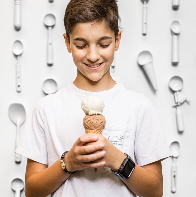 Boy holding double scoop of ice cream in a cone.