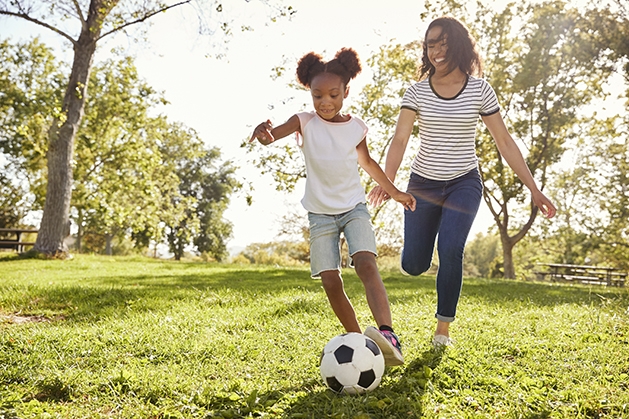 Woman and daughter playing soccer in the park