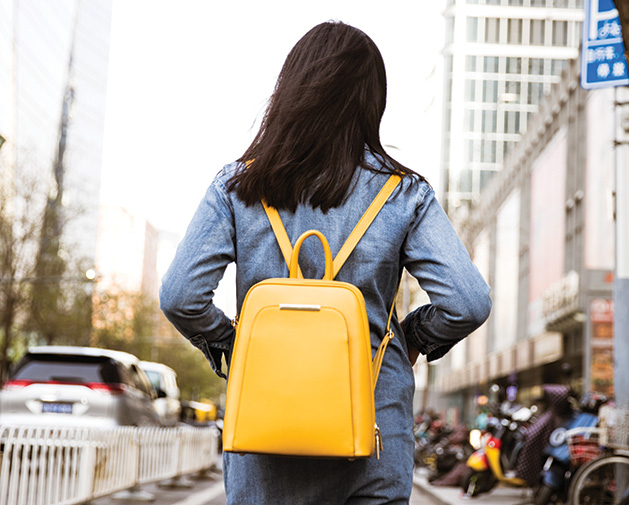 A woman wears a yellow backpack. Backpacks are a hot fall fashion trend, according to Wendy Witherspoon of Prink Style.