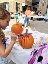 A girl painting a pumpkin.