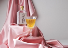 A bottle of Dampfwerk pear brandy sits alongside a glass on pink satin.