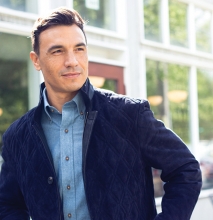 A man models a navy suede jacket blue chambray shirt from CircleRock