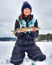 Woman holding fish caught while ice fishing