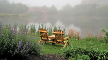 Two wooden chairs sit near the water in Centennial Lakes Park.
