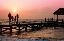 A family enjoys a sunset on the beach on their family vacation.