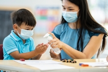 Masked woman and child using hand sanitizer