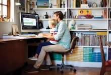 A father sits at an organized desk with his son.
