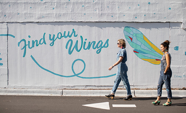 Two women walk past the mural painted on the side of the Vernon Avenue Caribou Coffee in Edina