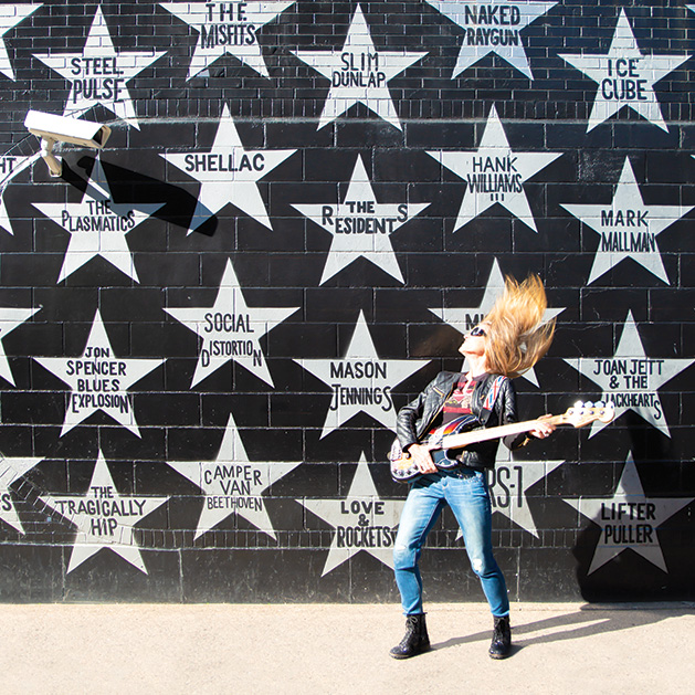 A woman plays a guitar outside of First Avenue in a shot from See Them Shine