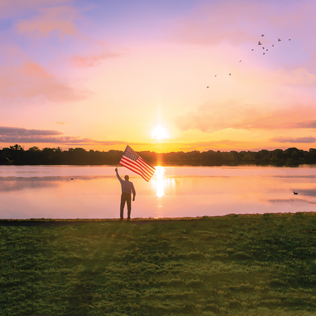 The sun sets on an Edina lake as a person holds an American flag in one of the shots from See Them Shine