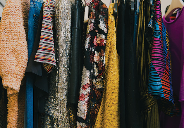 A variety of fall fashion pieces hang on a rack.