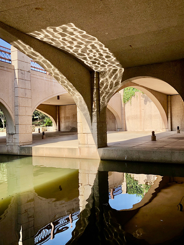 The arches under a bridge are reflected in the water at Centennial Lakes Park.