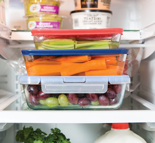 Fruit and vegetables in tupperware in a refrigerator.