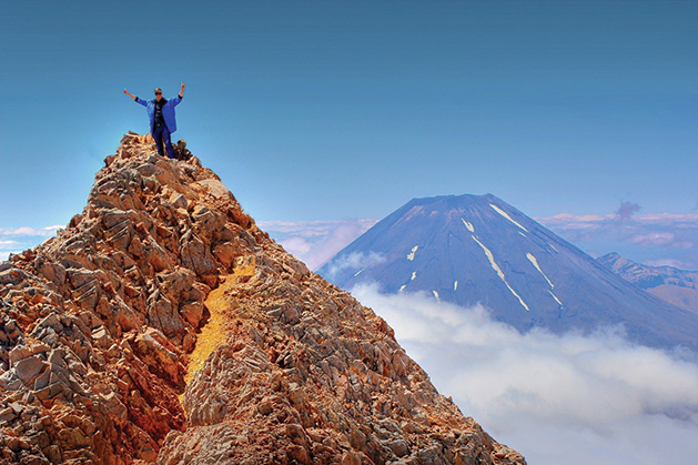 A person celebrates after climbing a mountain.